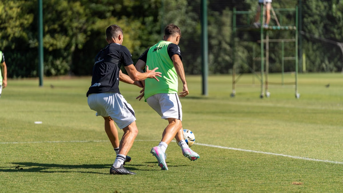 Players engaged in a soccer training session on a sunny outdoor field.